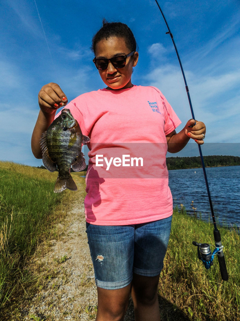 Woman with catch on riverside against sky