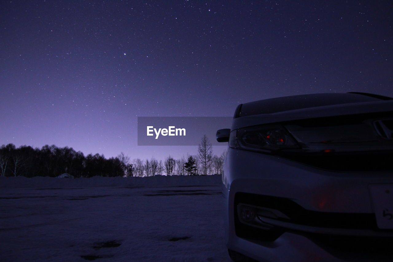 Car parked in field against sky with stars