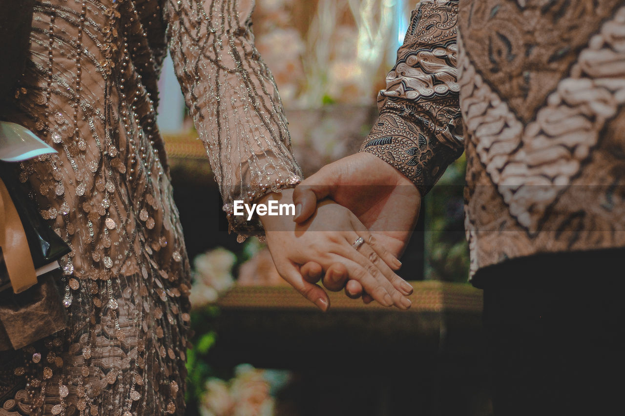 Midsection of couple holding hands outdoors