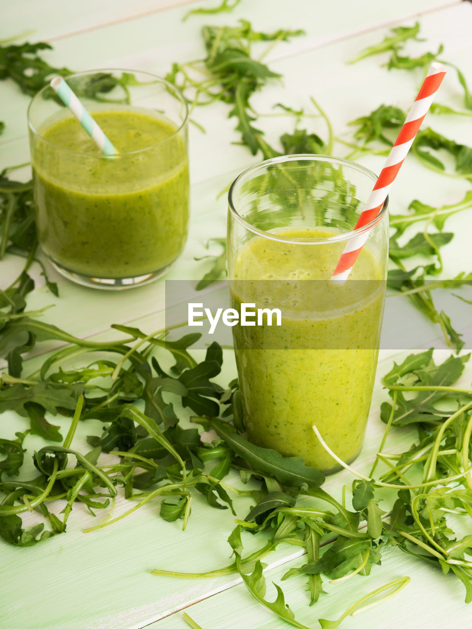 Smoothie in glasses and arugula on table