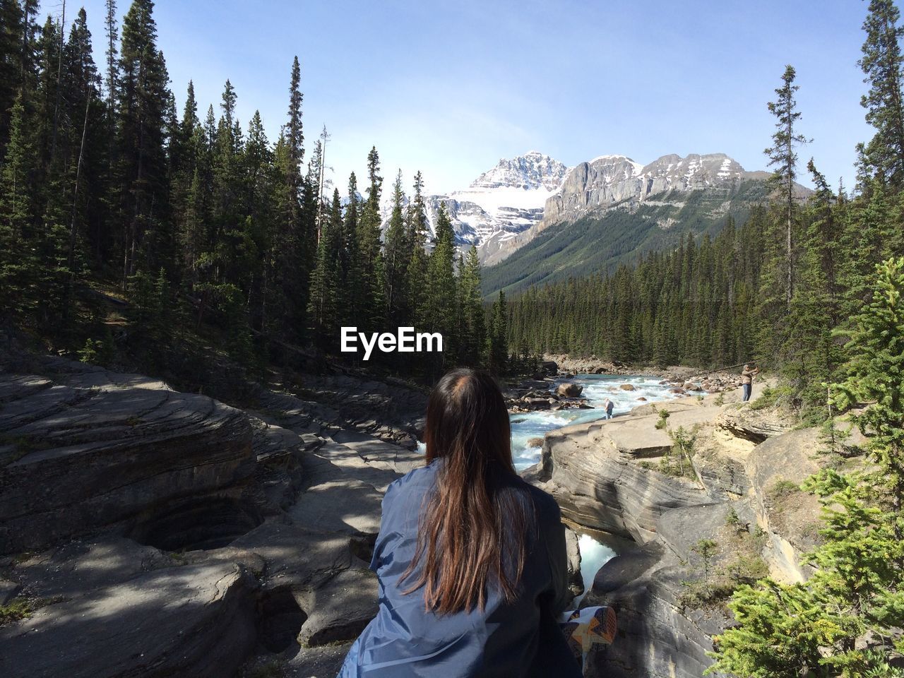 Rear view of woman standing by river in forest