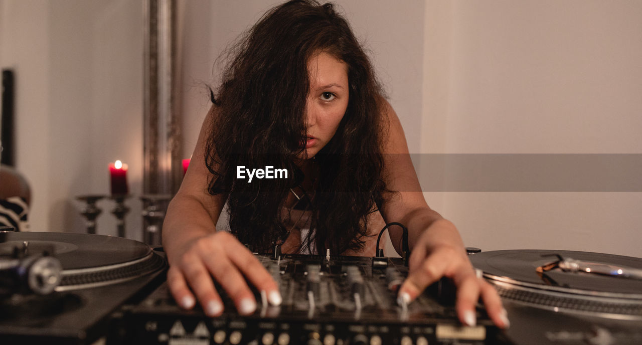 Close-up of fashionable young woman playing music at home