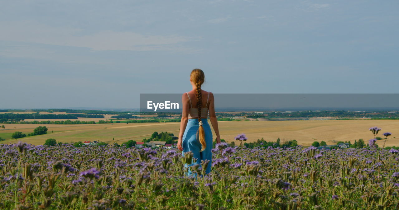 Harmony and unity with nature. rear view of woman in flower field.