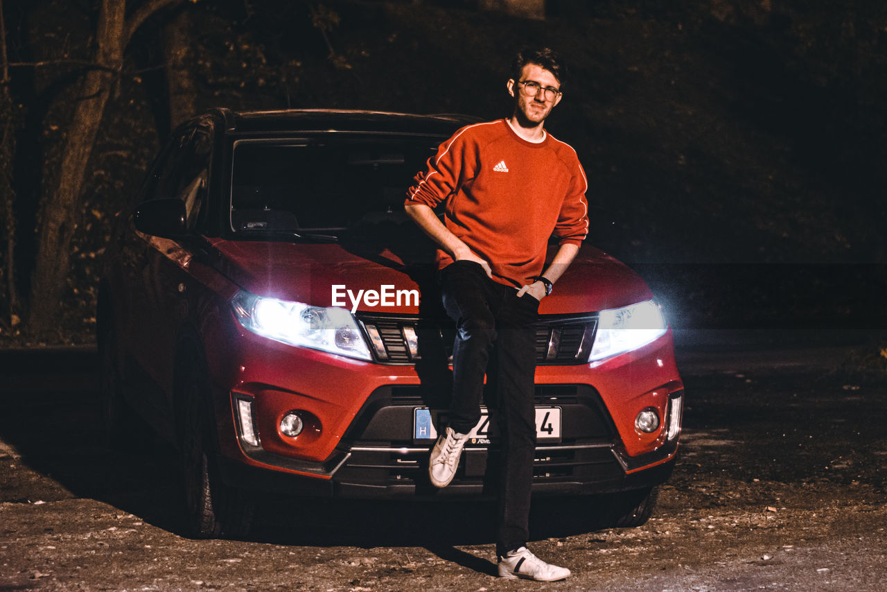 PORTRAIT OF MAN STANDING BY CAR