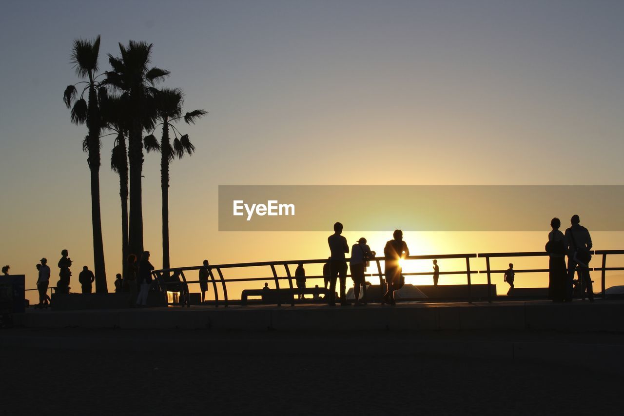 Silhouette people against clear sky during sunset