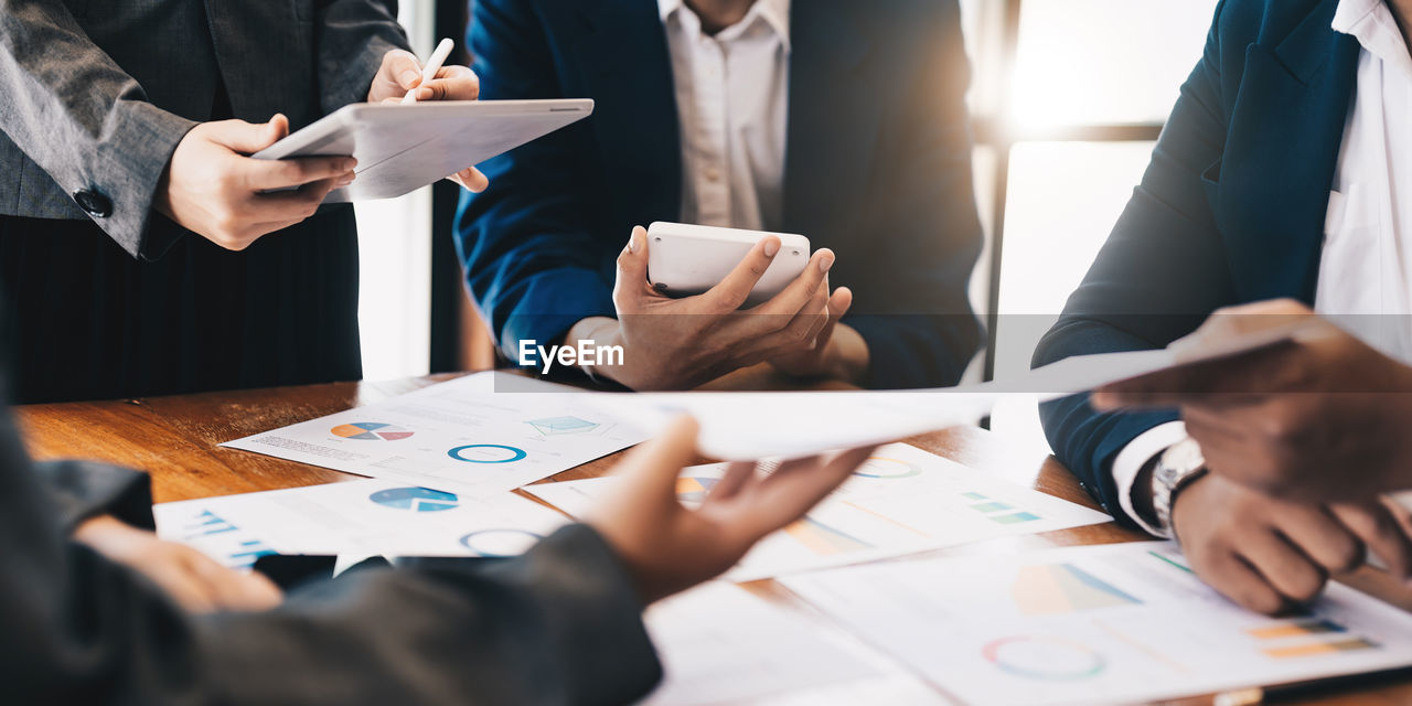 midsection of business people working on table