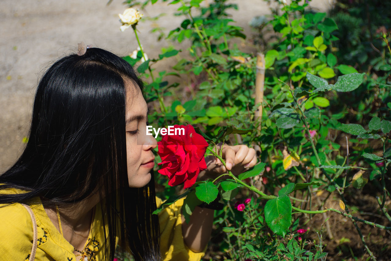 Woman smelling red rose outdoors