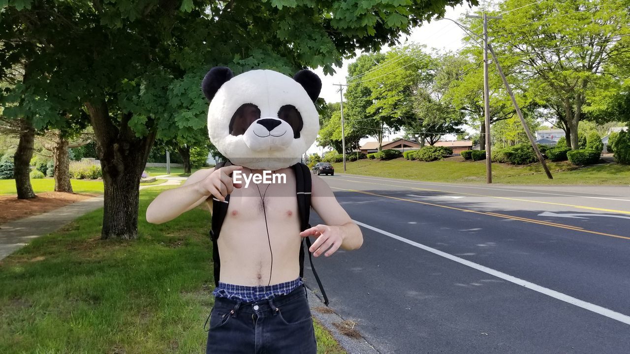 Person in a mask standing by road against trees