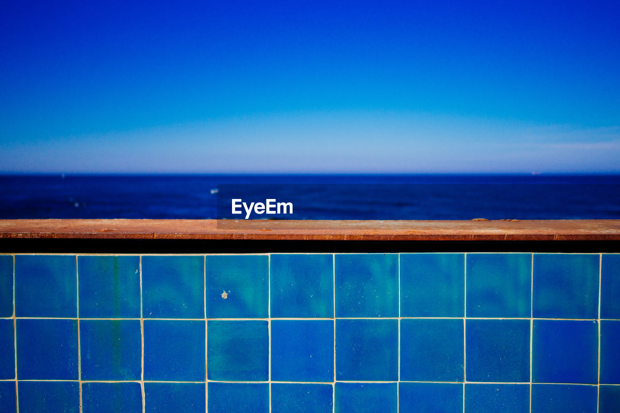 Blue tiled railing against sea