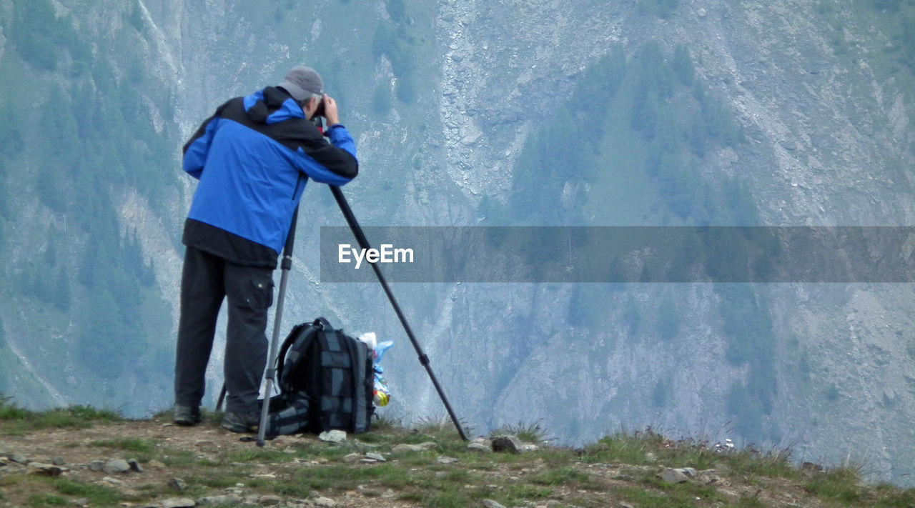 Rear view of man photographing mountains