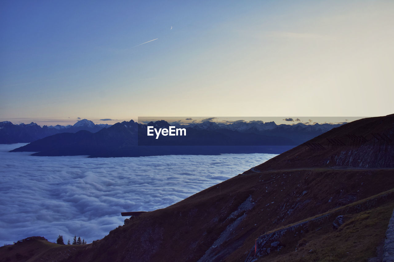 Scenic view of sea of clouds against clear sky during sunset