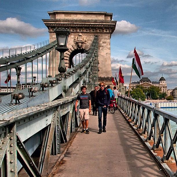 TOURISTS ON BRIDGE AGAINST CLOUDY SKY