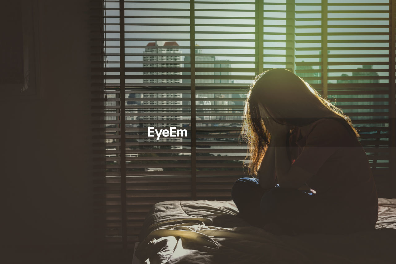 rear view of woman looking through window at home