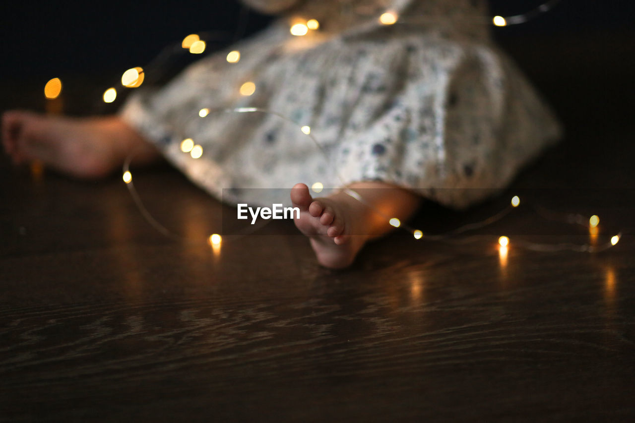 Lonely kid plays with an electric garland, cozy feet on the floor. children's safety 