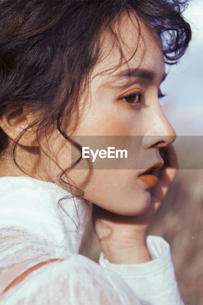 CLOSE-UP PORTRAIT OF WOMAN LOOKING AWAY OUTDOORS