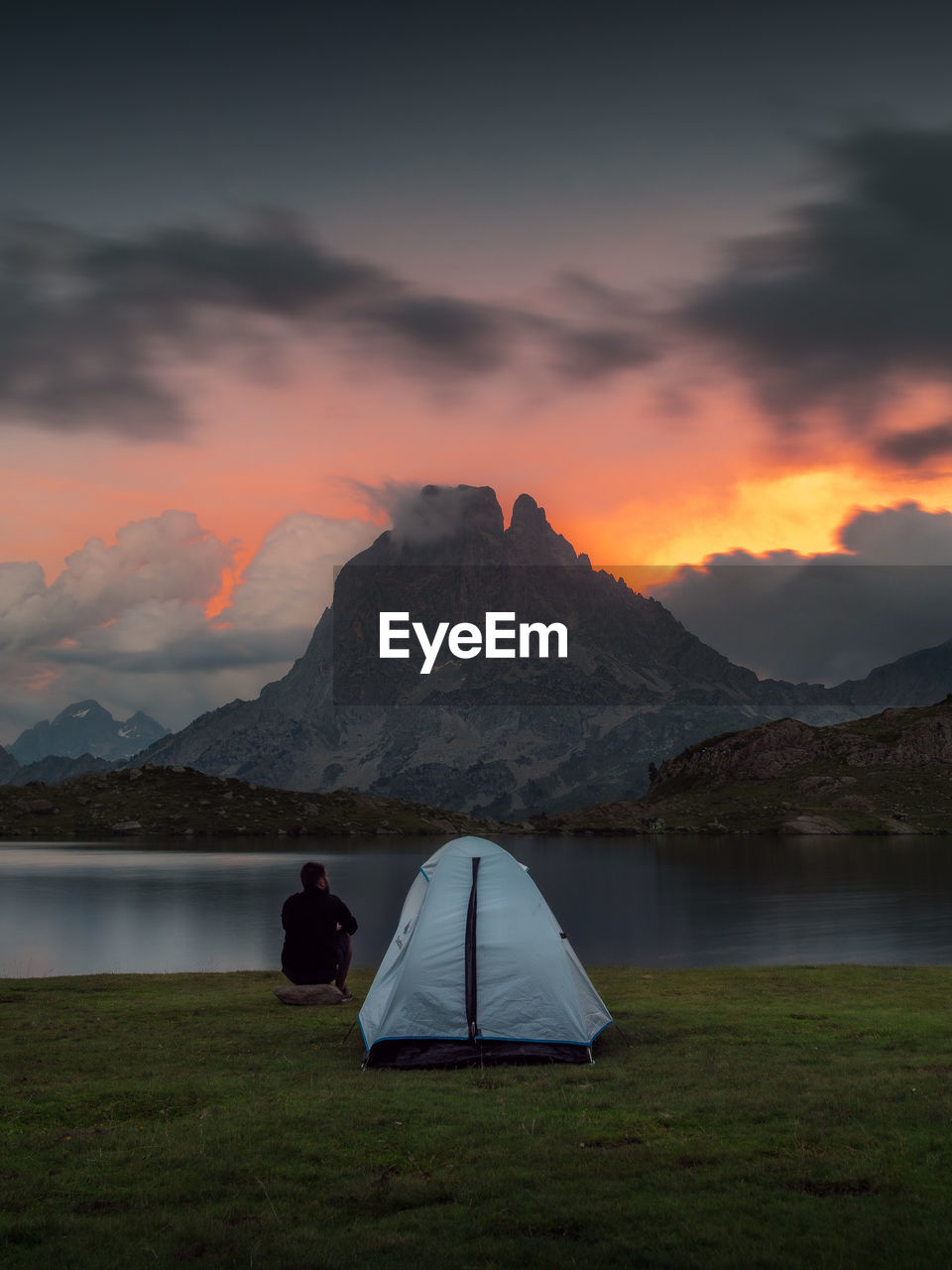 Rear view of man on lake against sky during sunset