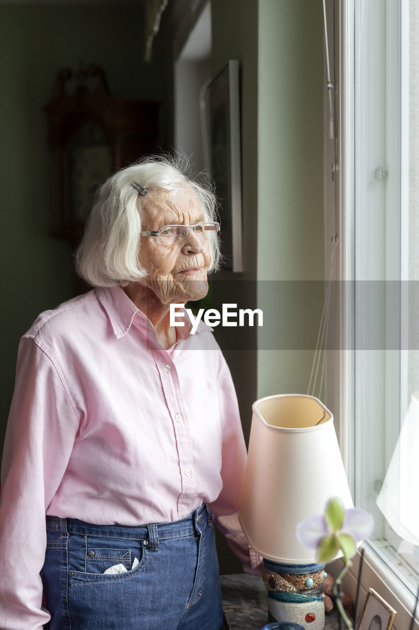 Senior woman looking through window