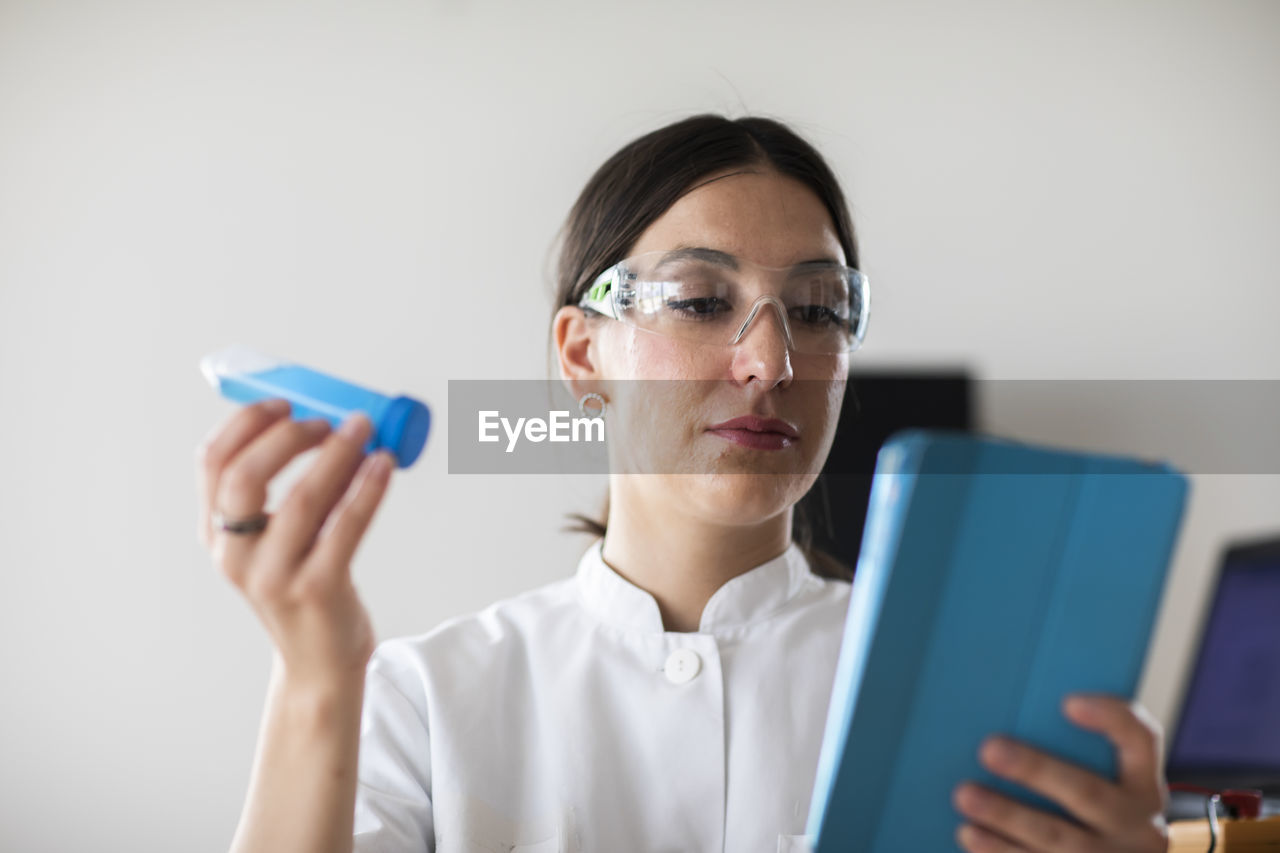 Scientist female with lab glasses, tablet and tubes in a lab