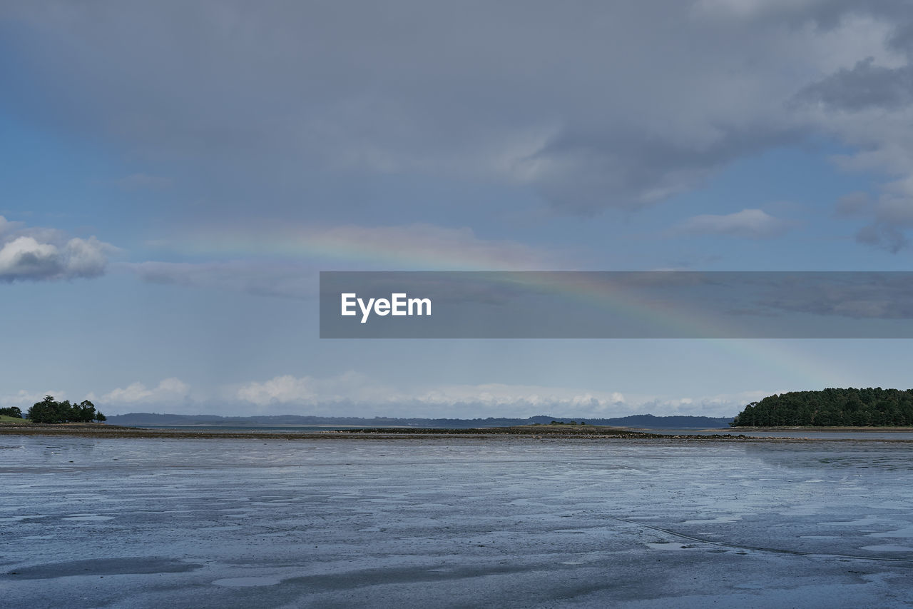 Scenic view of rainbow over sea against sky