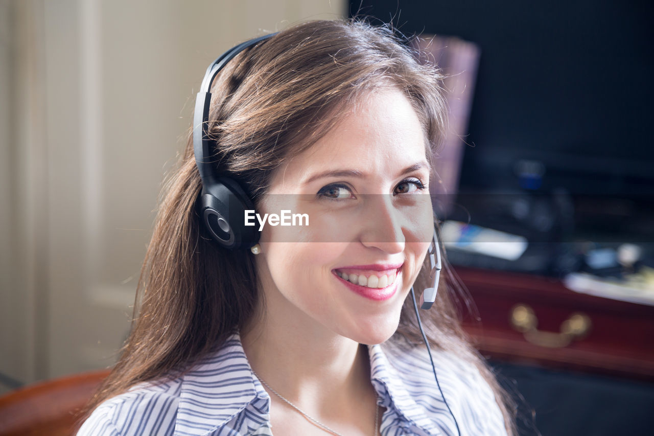 Portrait of smiling female customer service representative answering calls in office