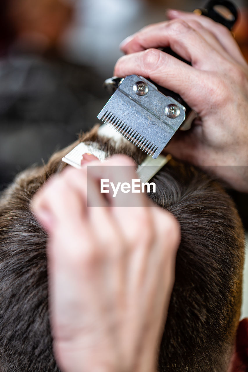 Cropped hands of barber cutting customer hair