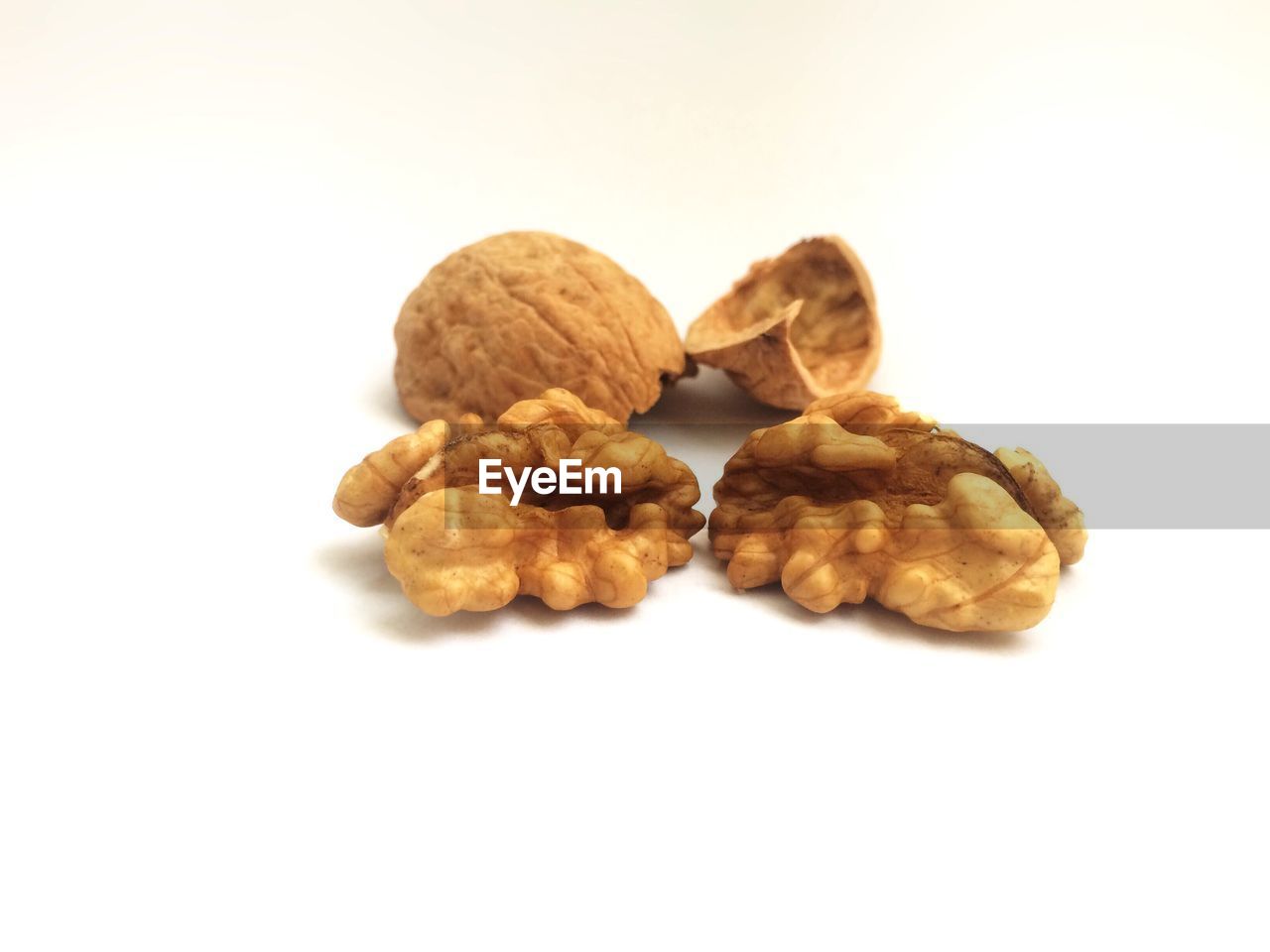 Close-up of walnut with broken shell on white background