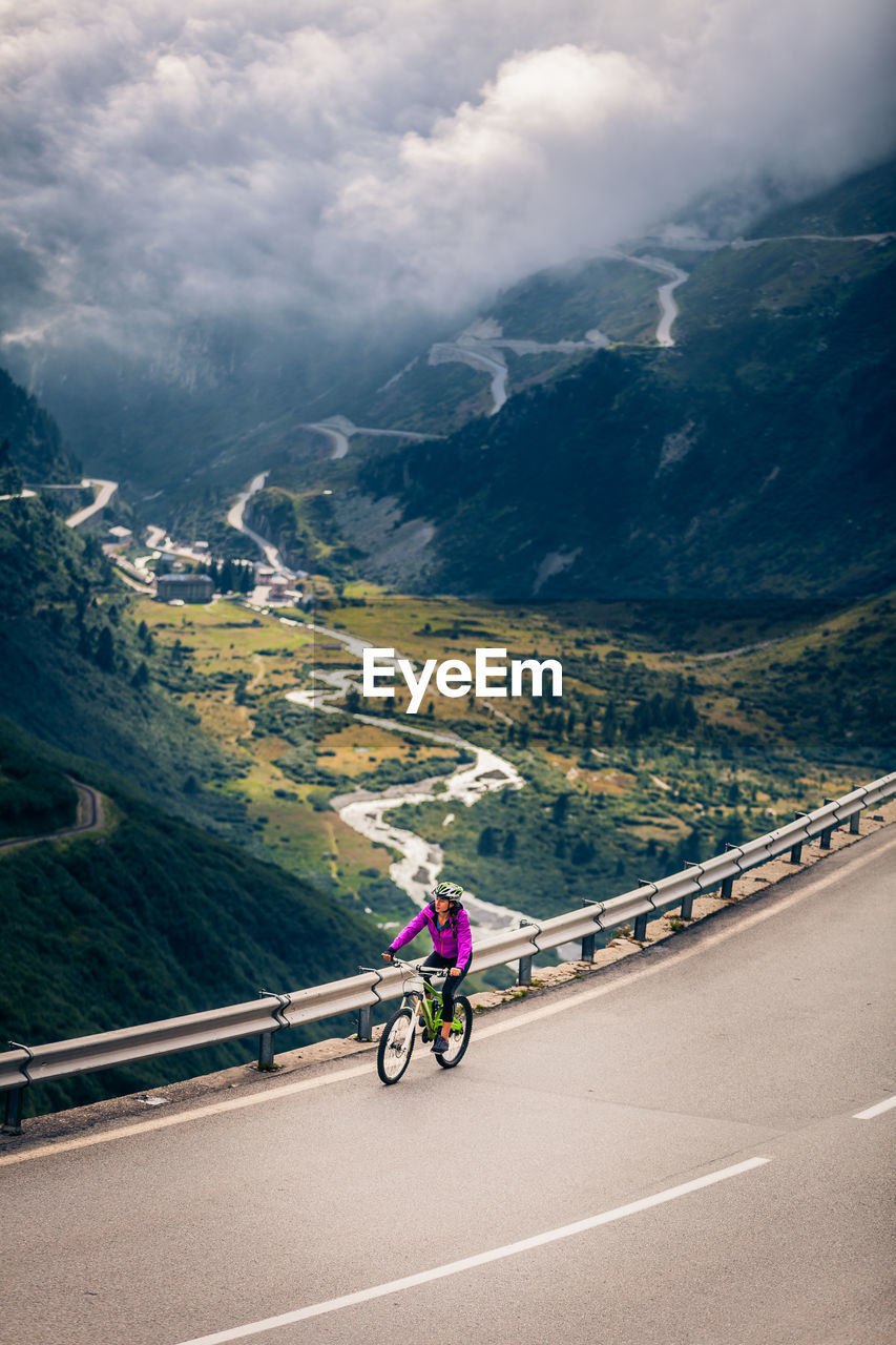 Woman riding bicycle on mountain road