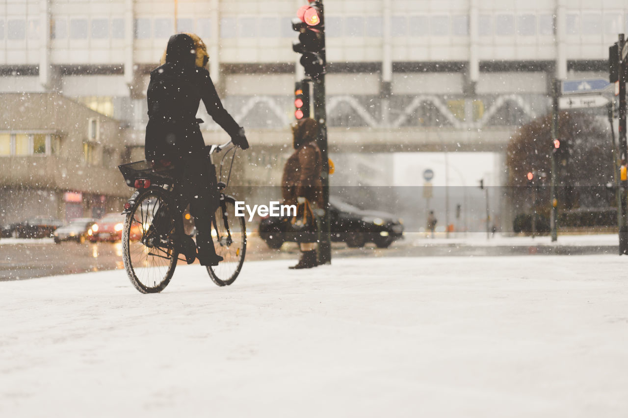Woman on bicycle in snow covered city