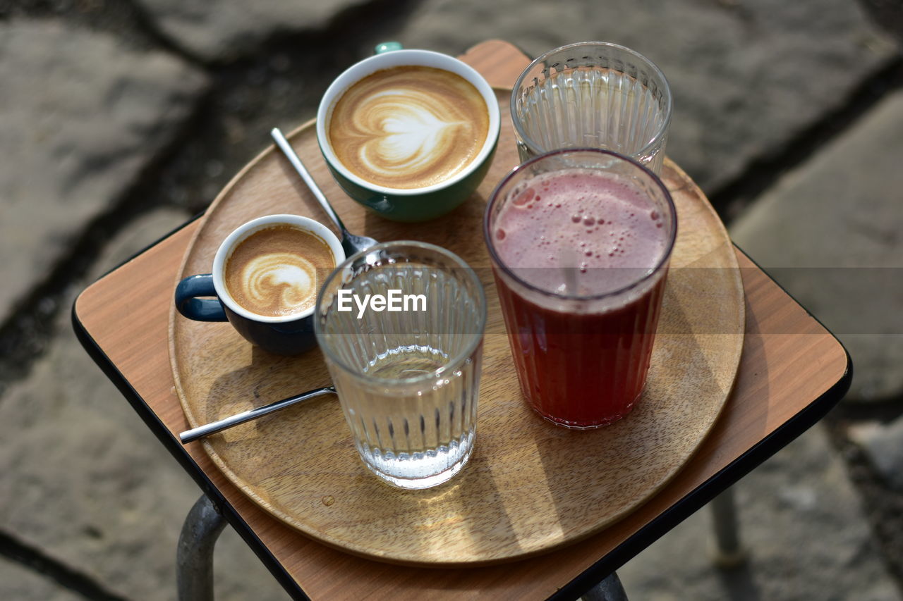 food and drink, drink, refreshment, table, coffee, food, glass, high angle view, wood, drinking glass, household equipment, still life, coffee cup, cup, no people, freshness, mug, cafe, kitchen utensil, eating utensil, day, frothy drink, crockery, alcoholic beverage, hot drink, outdoors, tray