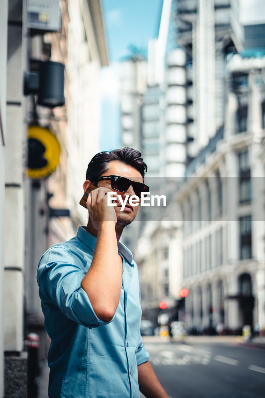 Man answering smart phone while standing in city