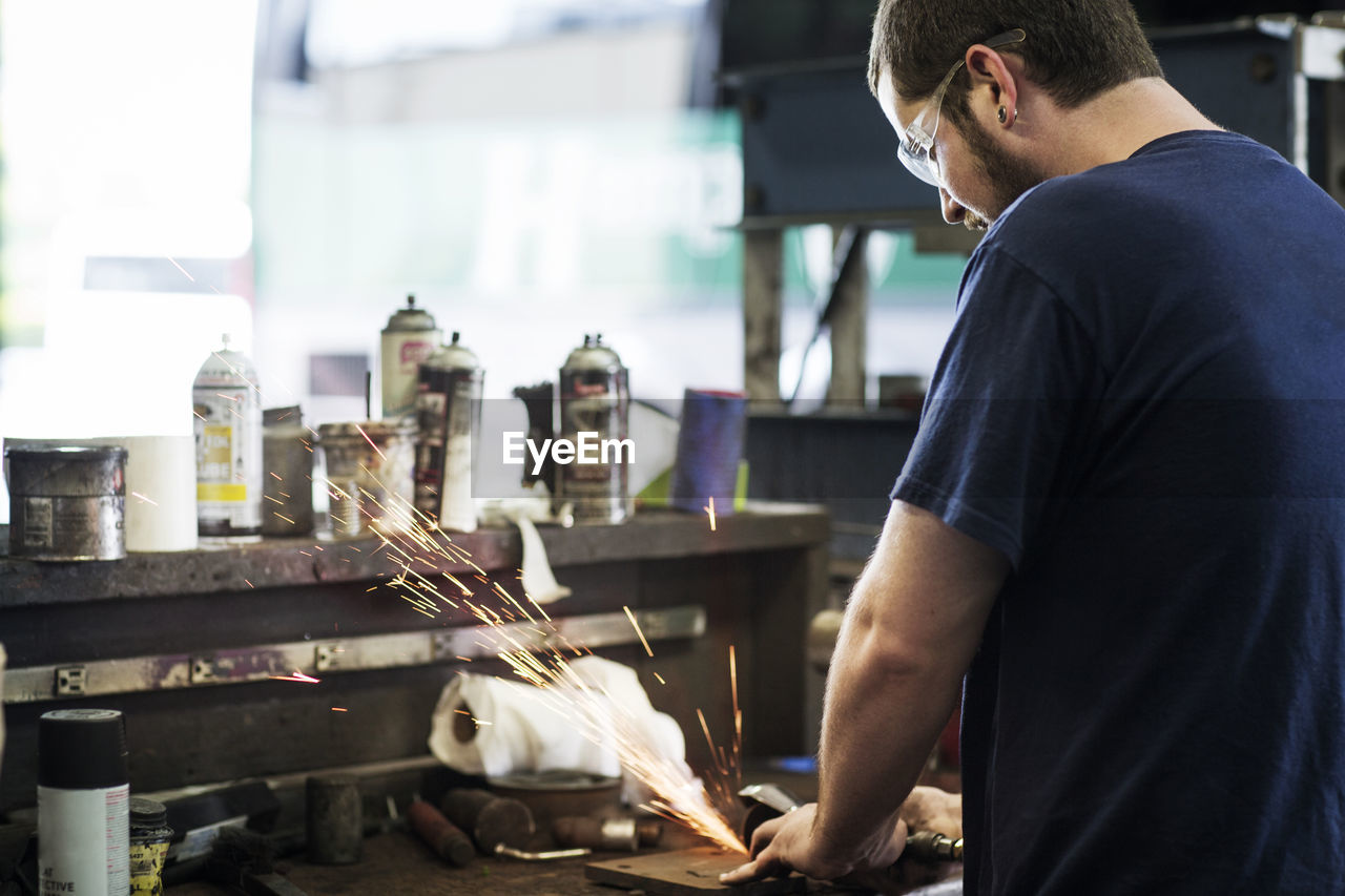 Mechanic grinding metal in workshop