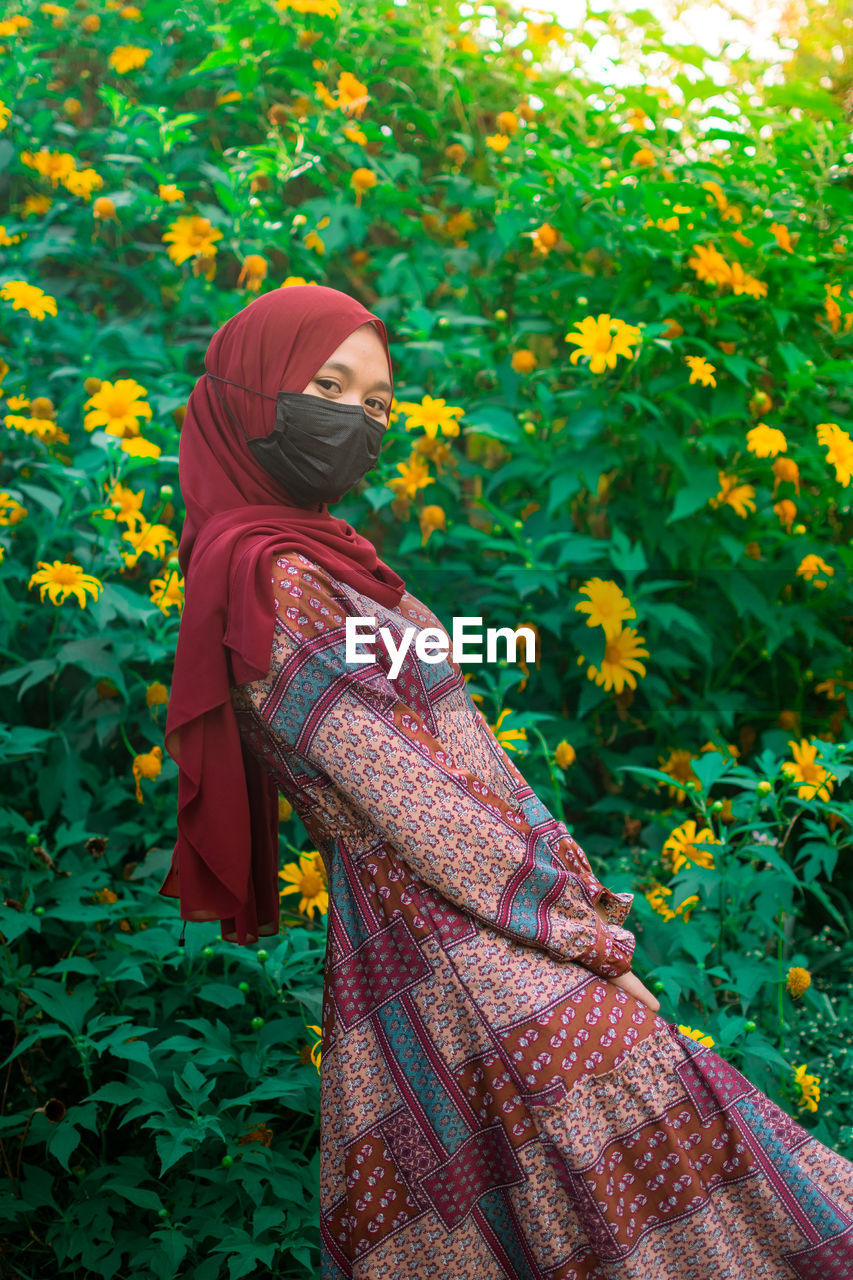 Rear view of woman standing amidst plants