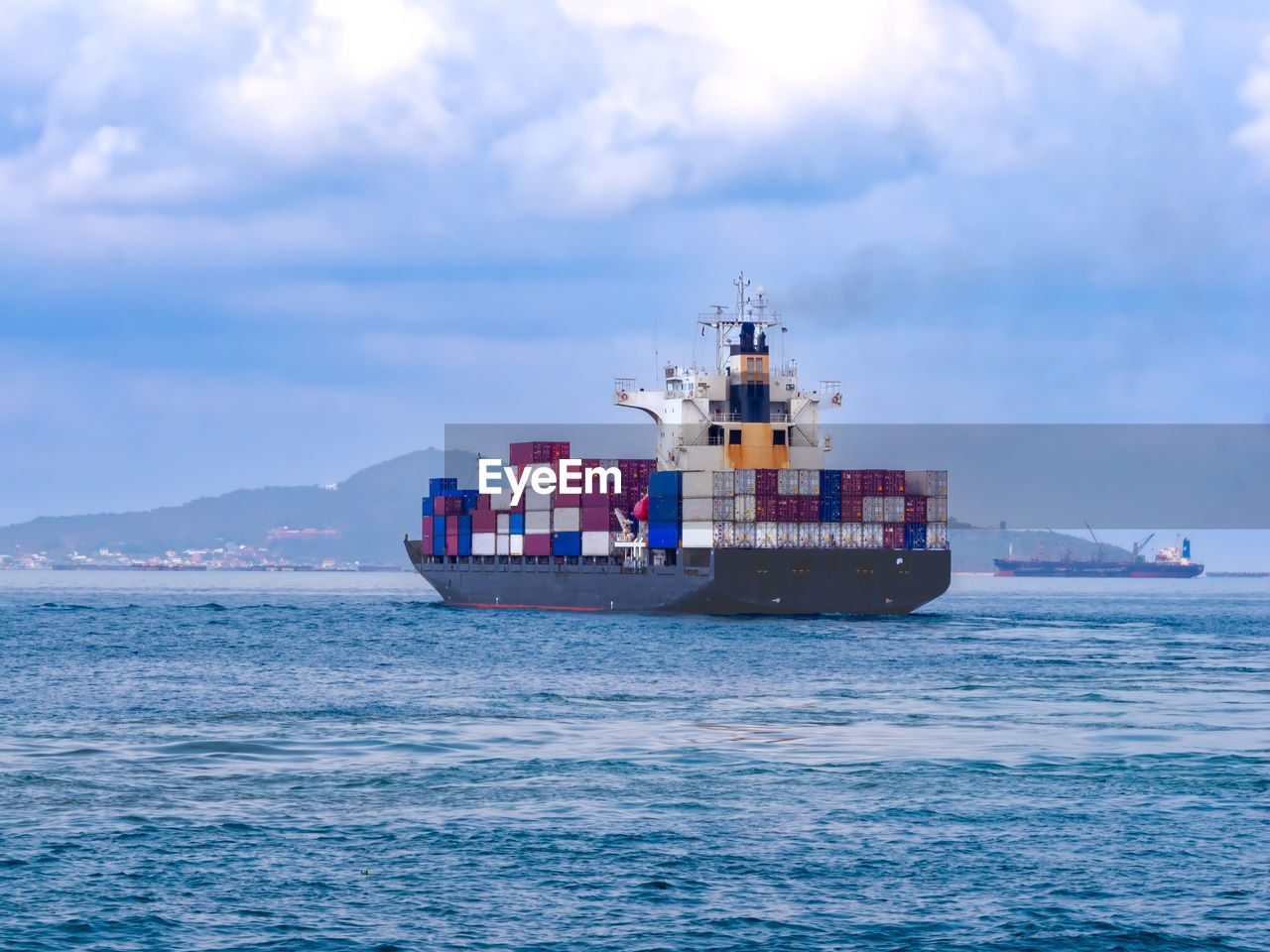 A container ship arriving to industial port on smooth sea.