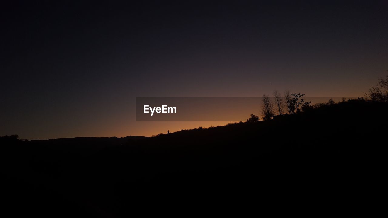 SILHOUETTE LANDSCAPE AGAINST CLEAR SKY DURING SUNSET