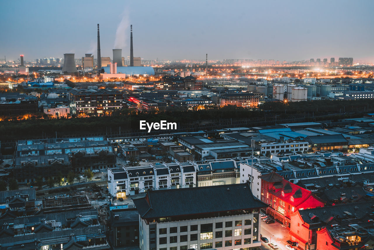 HIGH ANGLE VIEW OF ILLUMINATED BUILDINGS IN CITY AGAINST SKY