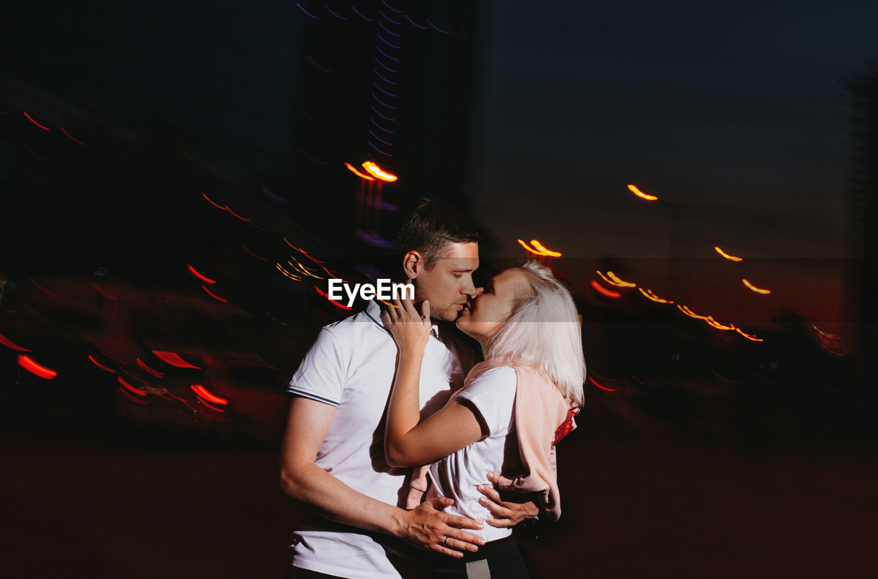 Couple kissing while standing outdoors at night