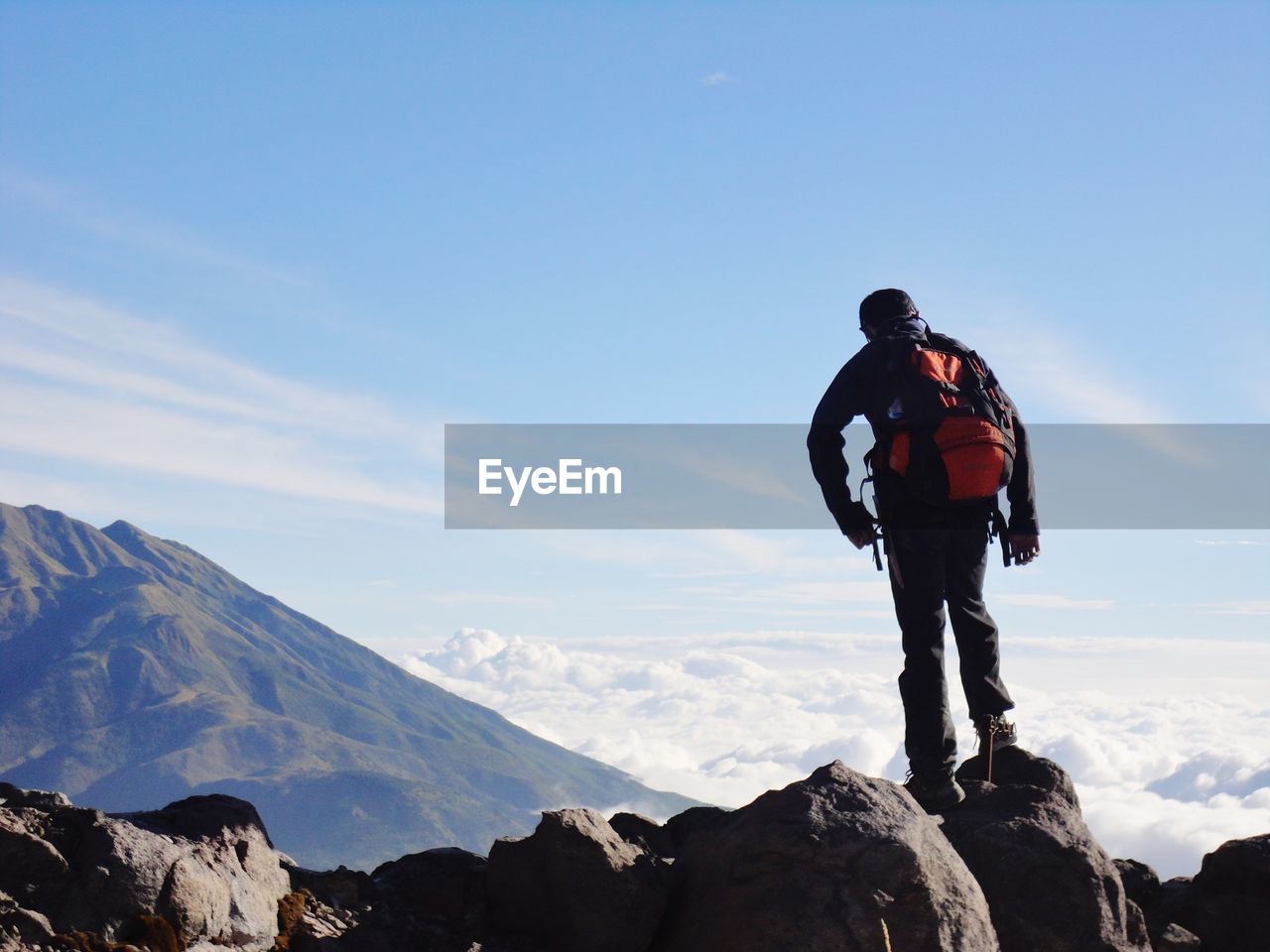 Man standing on rock against sky