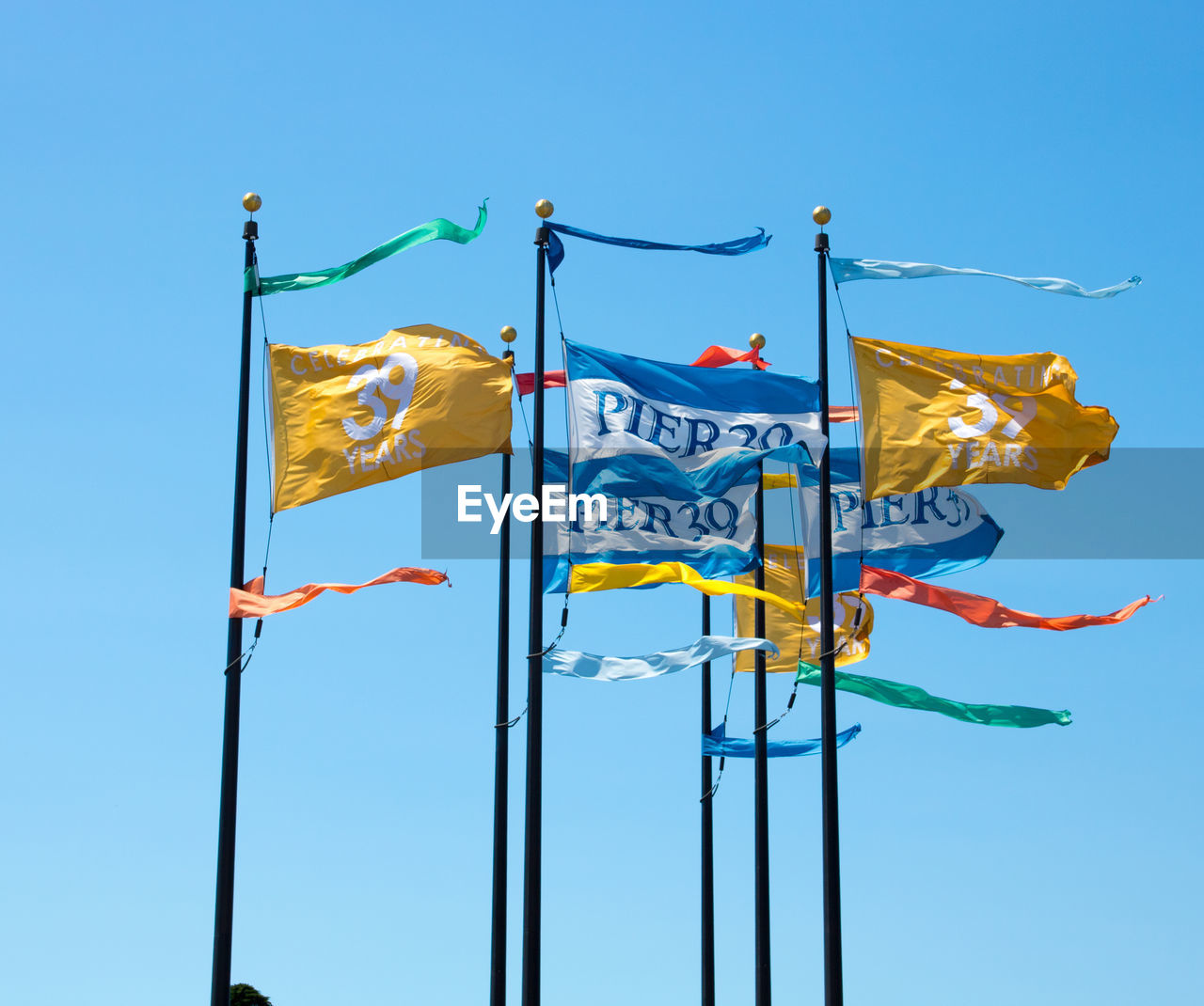 LOW ANGLE VIEW OF FLAGS AGAINST BLUE SKY