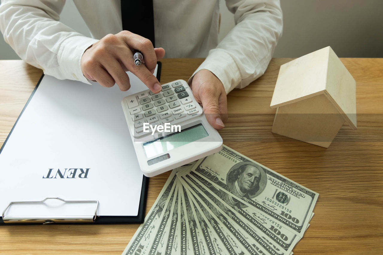 Midsection of businessman calculating on table