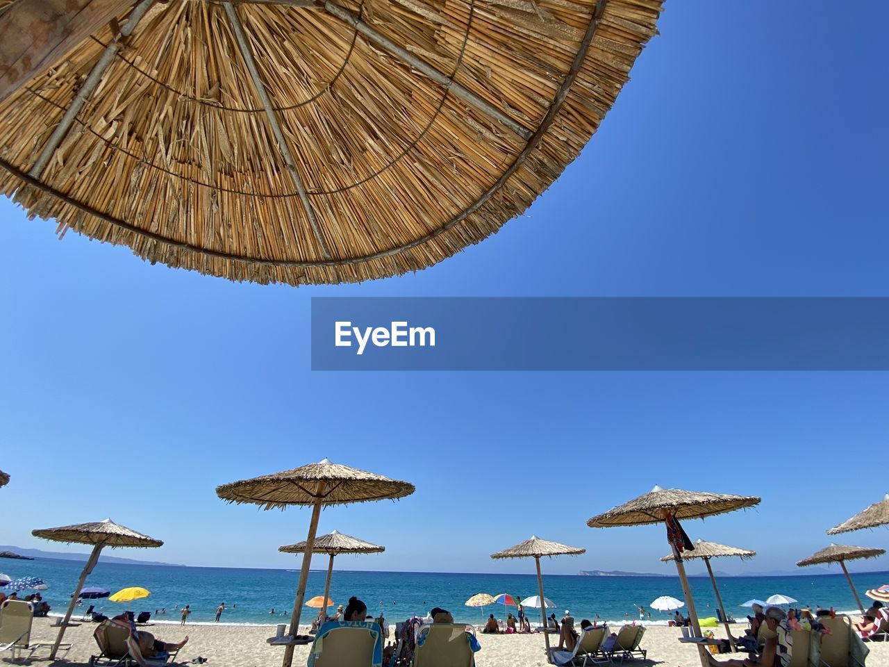 PEOPLE ON BEACH AGAINST CLEAR SKY