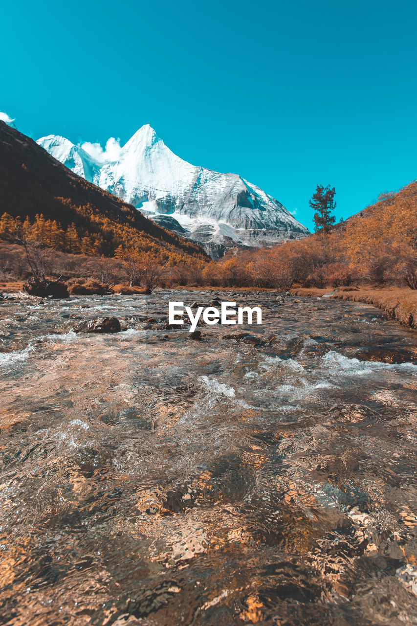 Scenic view of snowcapped mountains against clear blue sky