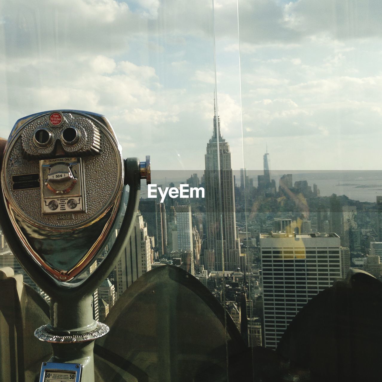 Coin-operated binoculars at observation point by empire state building against sky
