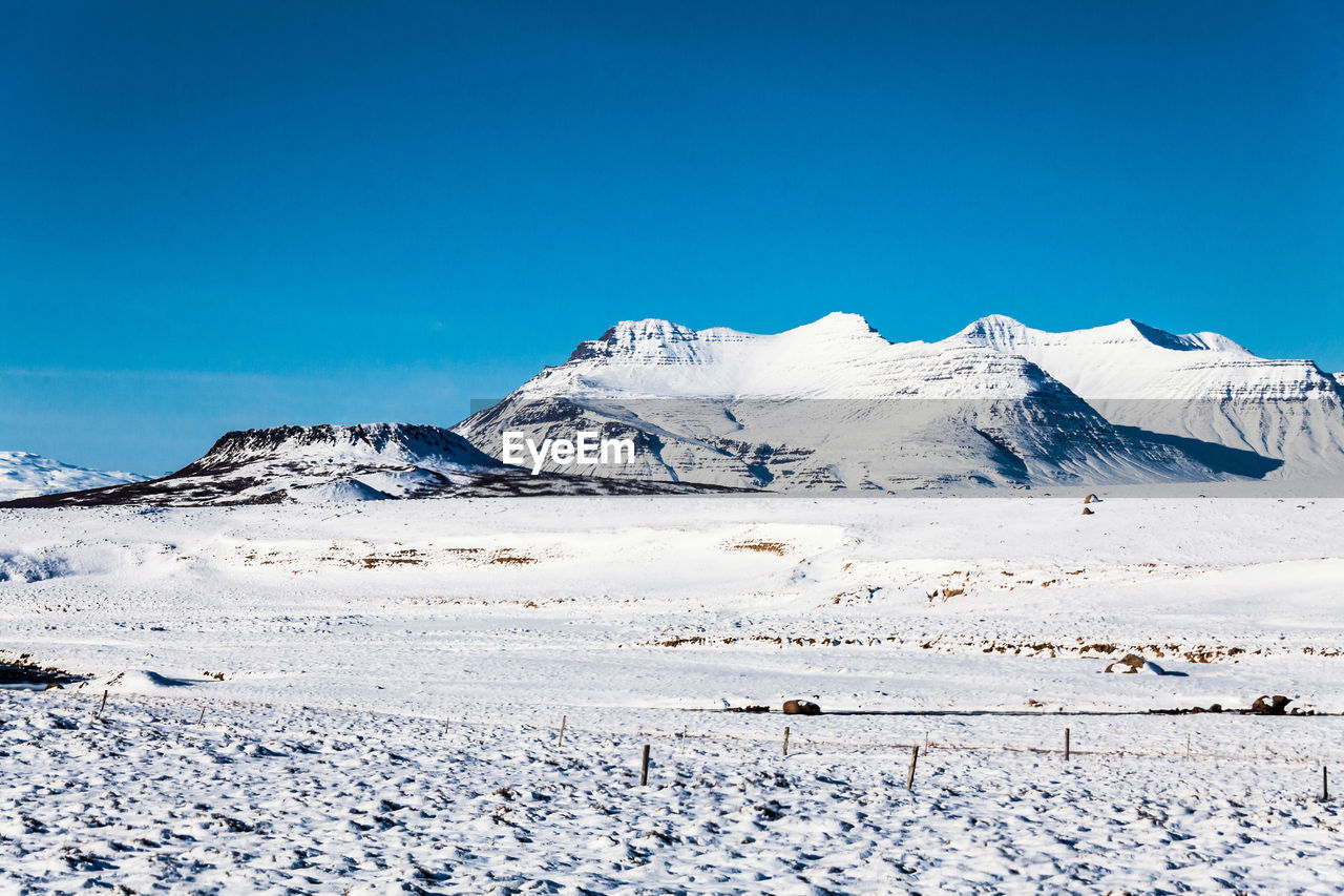 Scenic view of snowcapped mountains against clear blue sky