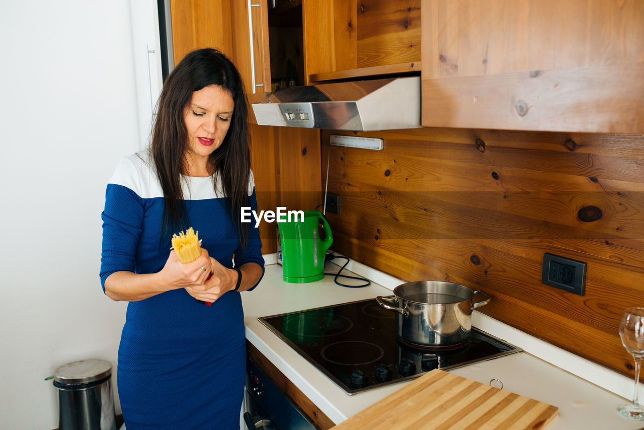 Woman preparing spaghetti in kitchen at home