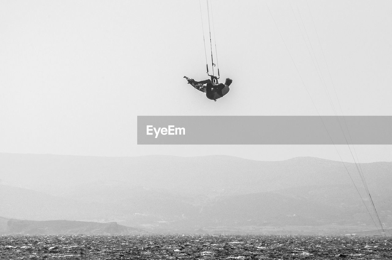 LOW ANGLE VIEW OF MAN PARAGLIDING AGAINST SKY