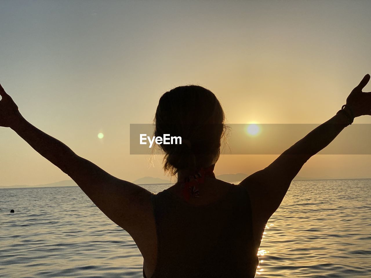 REAR VIEW OF SILHOUETTE WOMAN IN SEA AGAINST SKY