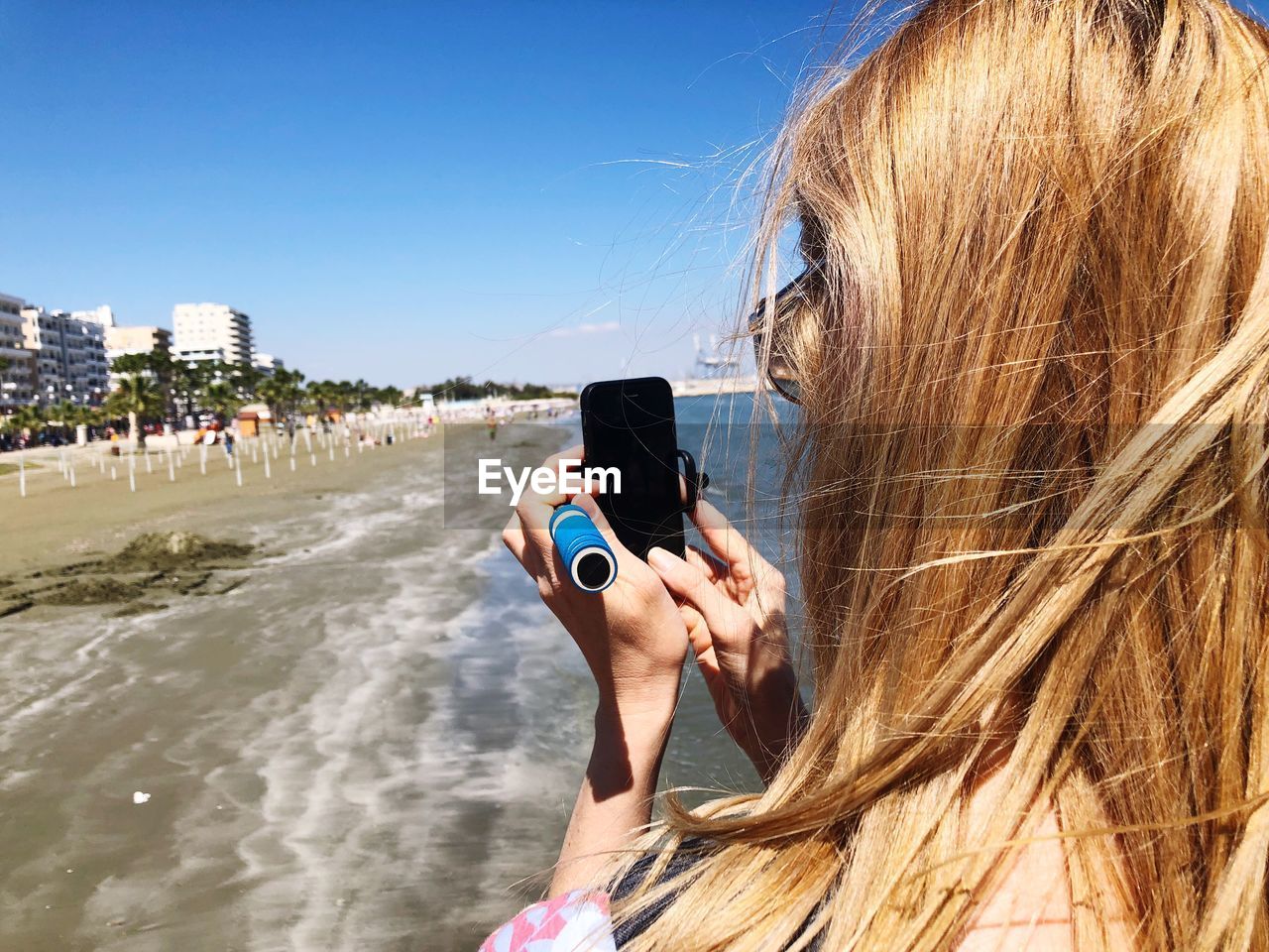 Close-up of woman with blond hair using mobile phone at beach