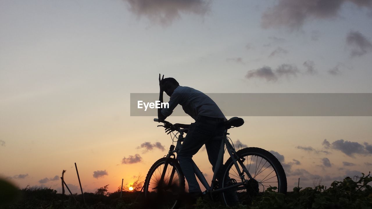 Man cycling against sky during sunset