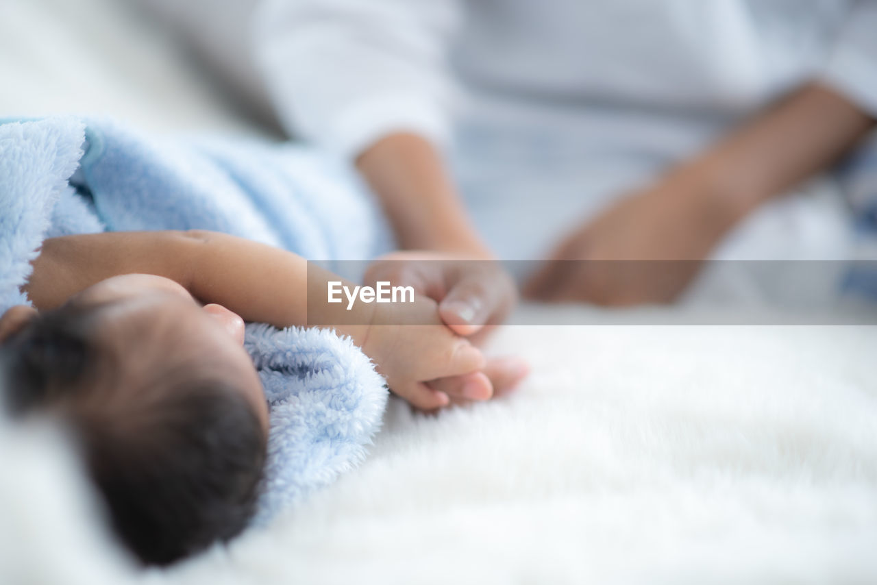 CLOSE-UP OF BABY GIRL LYING ON BED