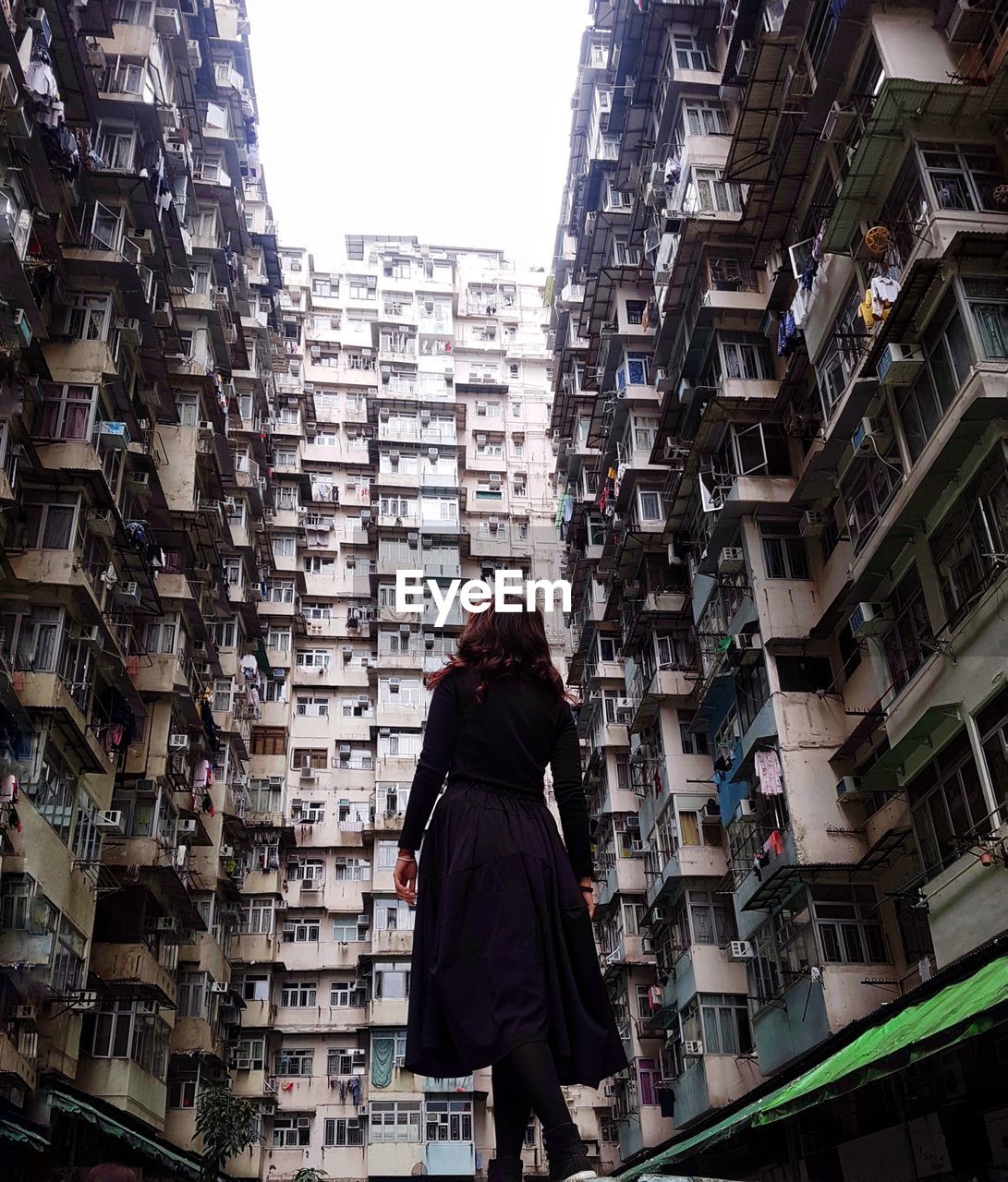 Rear view of woman standing amidst buildings